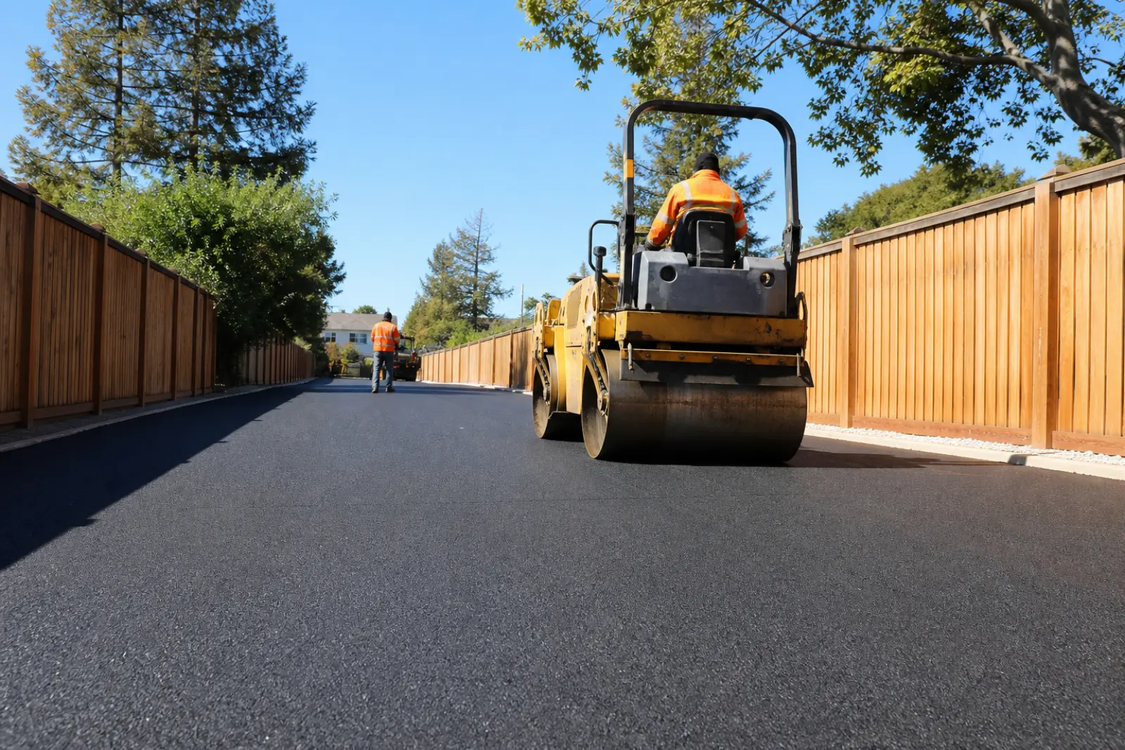Steel drum roller compacting a freshly paved private court