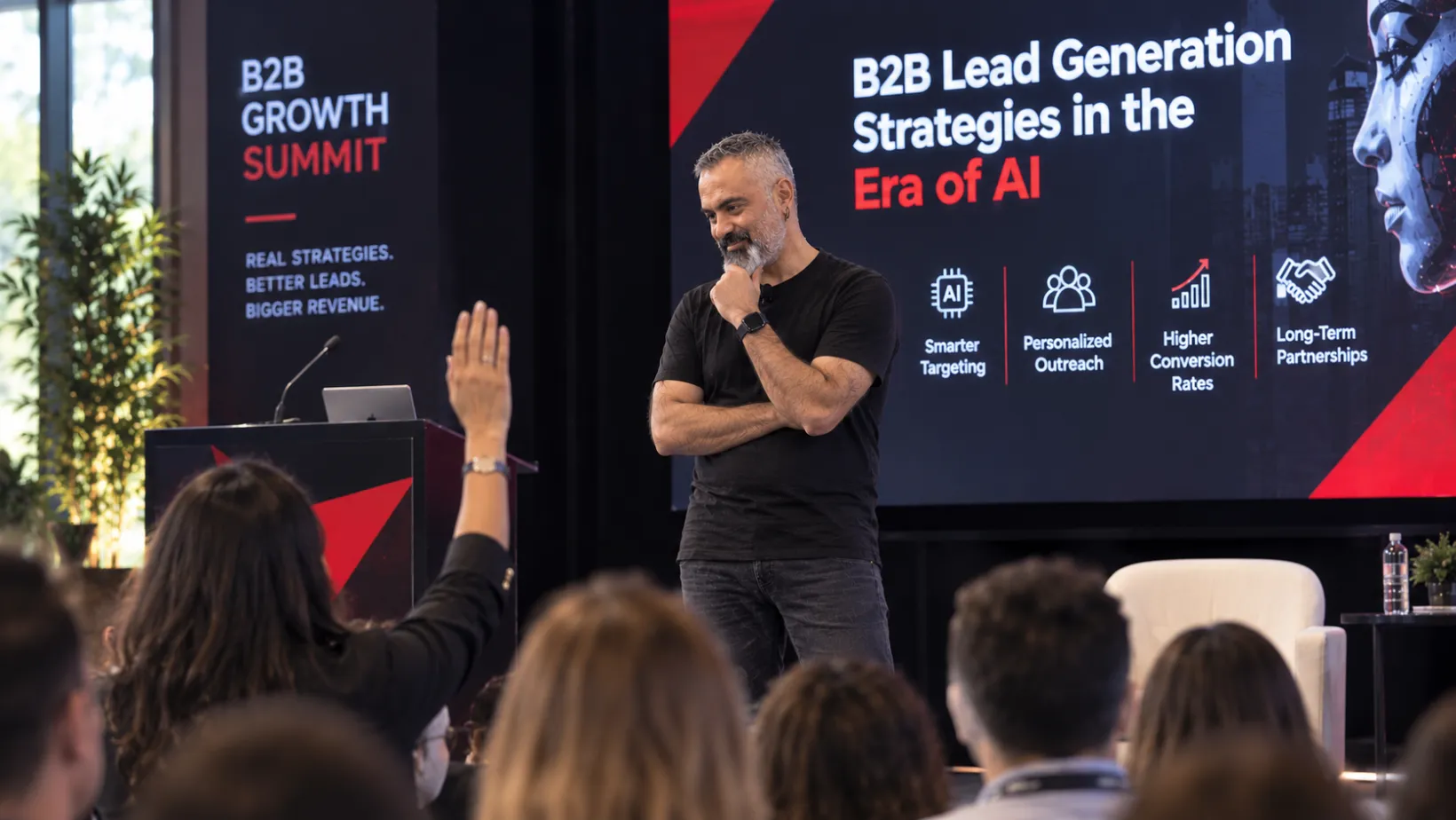 Speaker on stage at a B2B growth summit as an audience member raises a hand