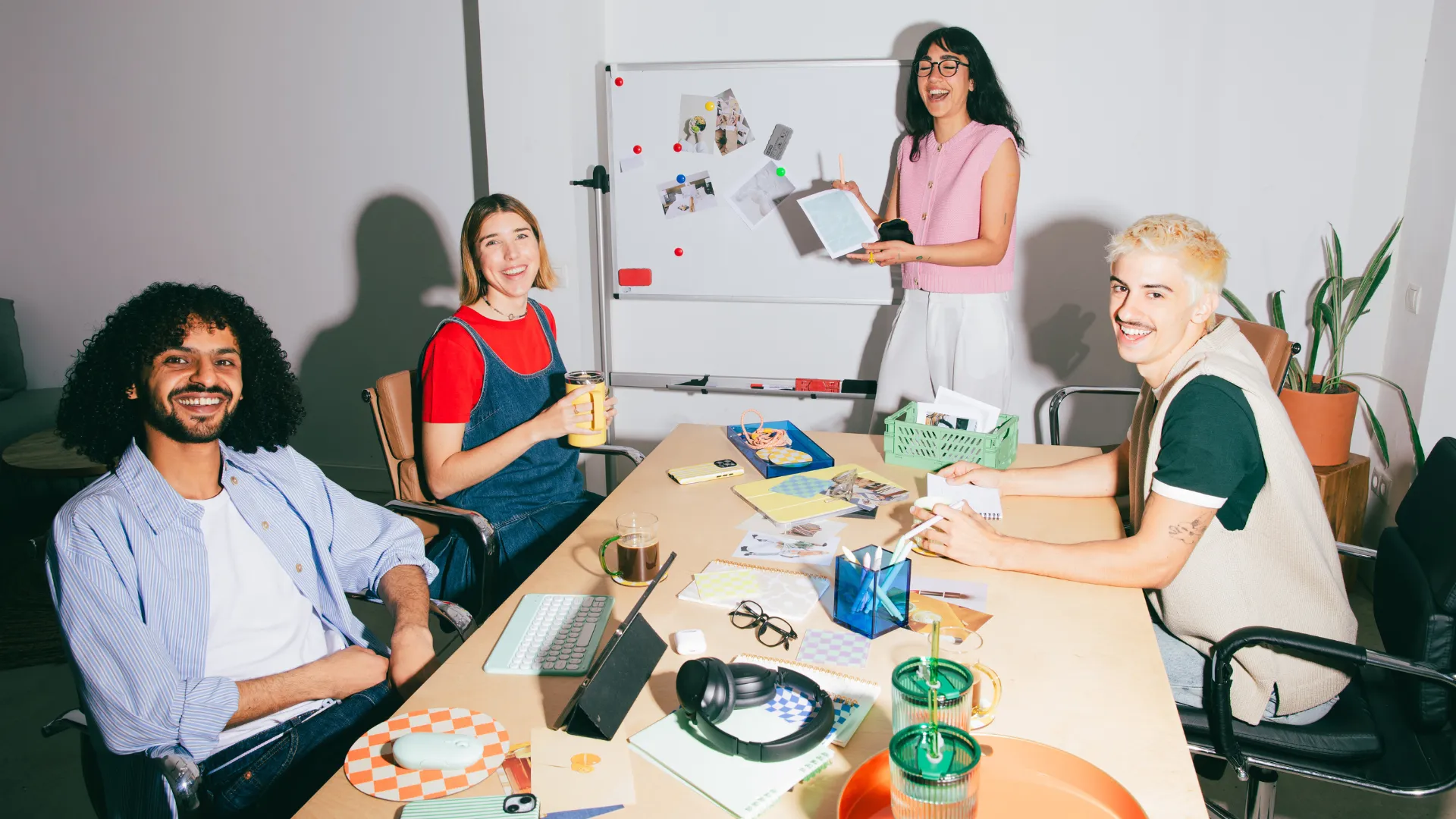 Smiling team around a meeting table in front of a whiteboard