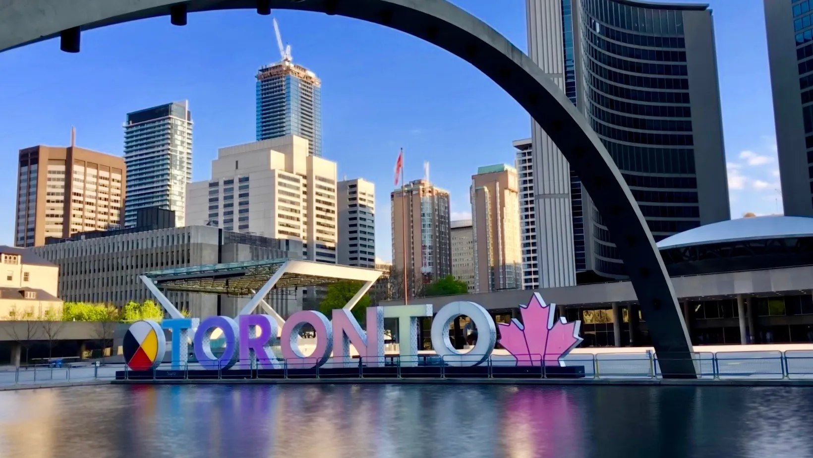 Colourful Toronto sign at Nathan Phillips Square under the City Hall arch