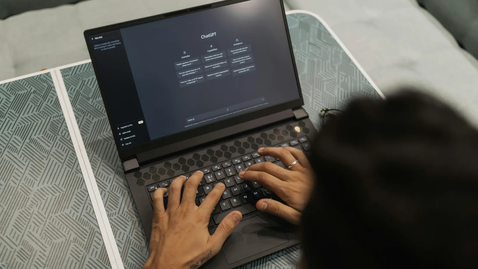 Overhead view of hands typing on a laptop with ChatGPT open