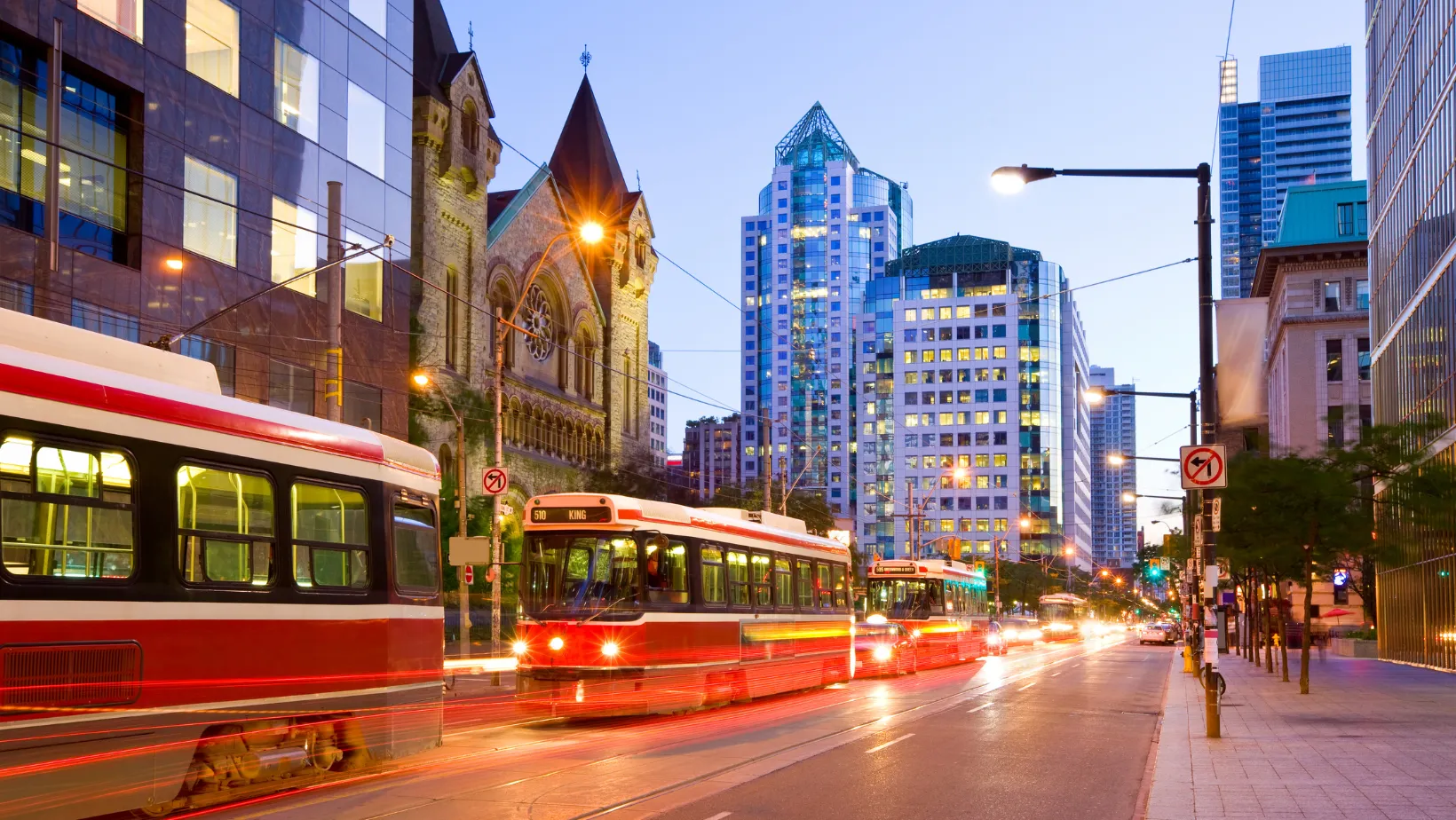 Red TTC streetcars on King Street in downtown Toronto at dusk