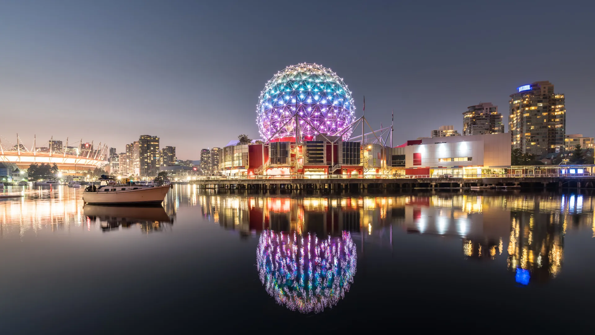 Science World dome lit up at night on False Creek in Vancouver