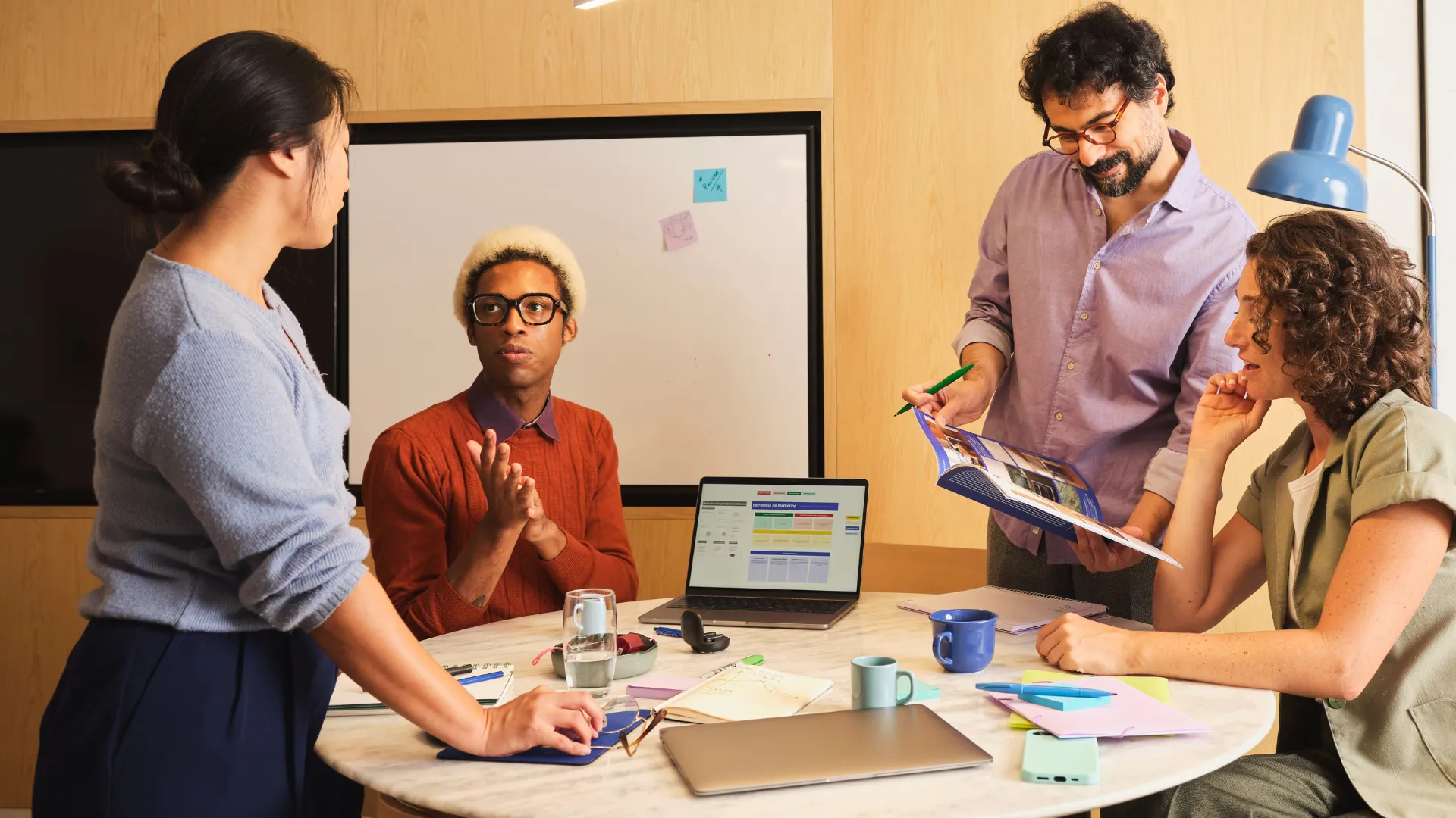 Team discussing a printed report around a round table with a laptop