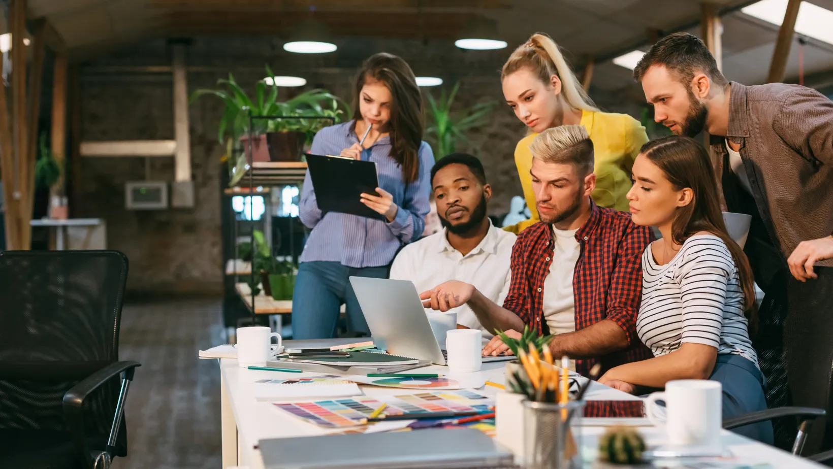 Marketing team gathered around a laptop reviewing a campaign in a bright office