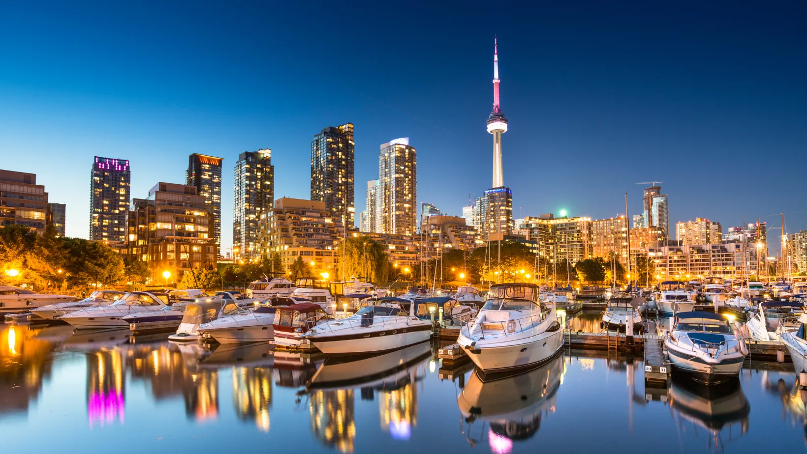 Toronto skyline and CN Tower at dusk above a marina full of boats