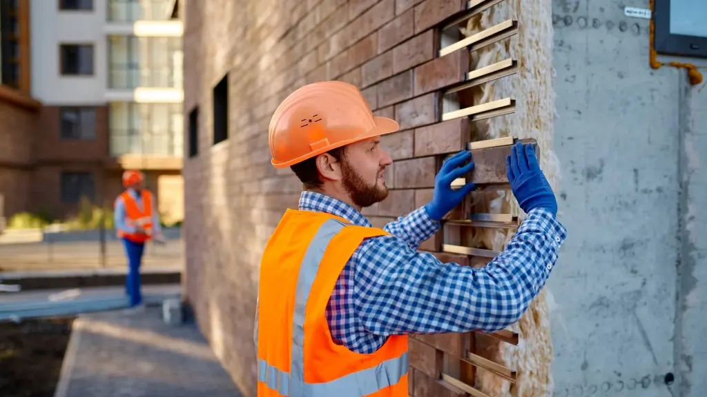 Contractor installing brick-effect exterior cladding panels on a rainscreen rail system