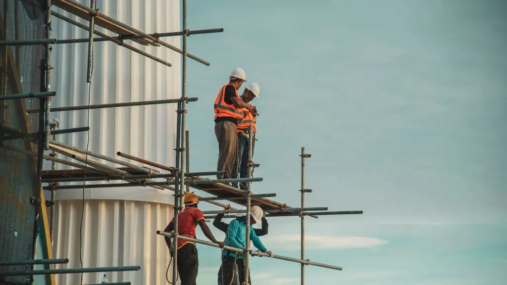 Cladding crew working from scaffolding beside a vertically ribbed industrial facade