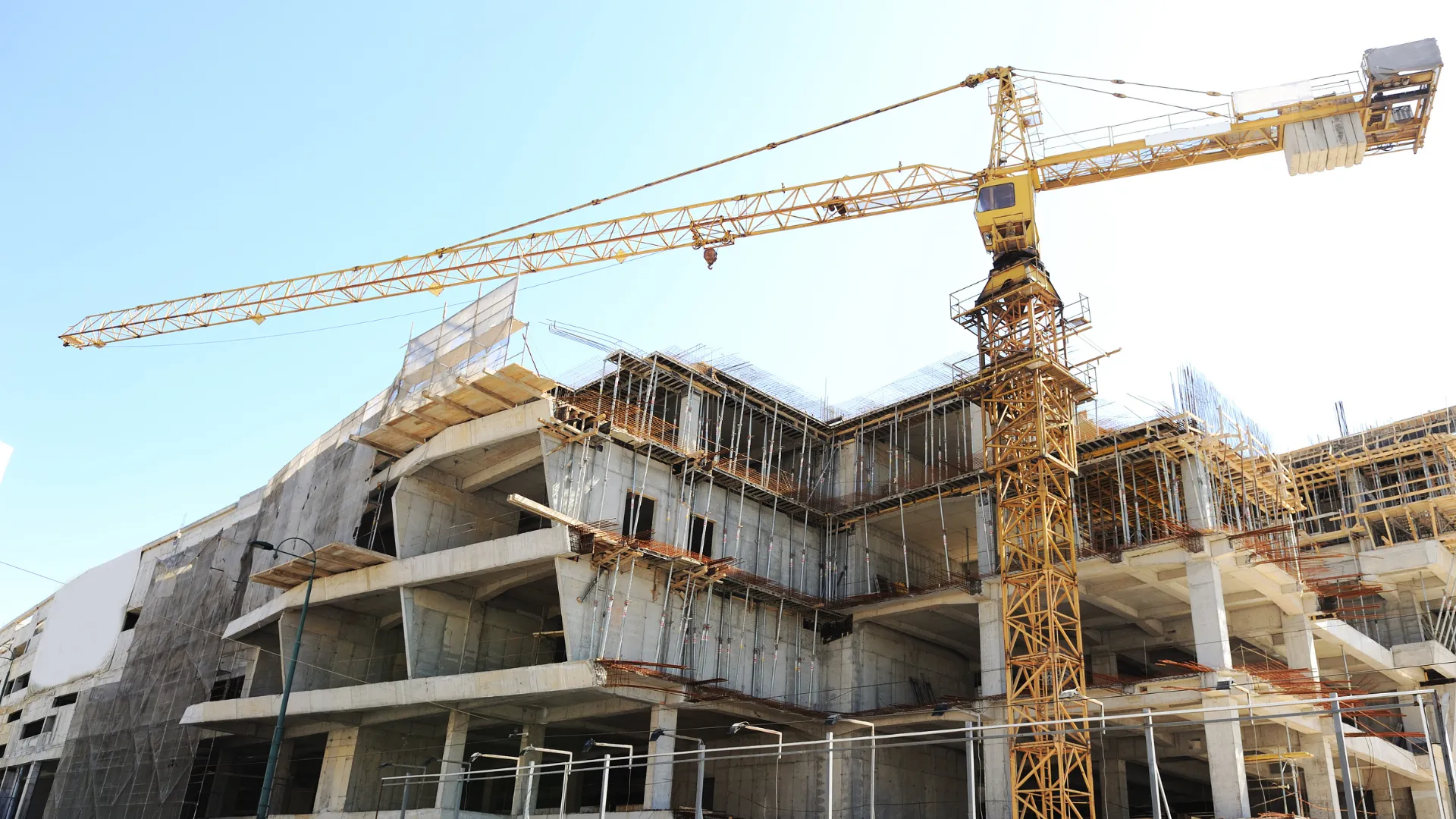 A tower crane stands over a concrete commercial building under construction