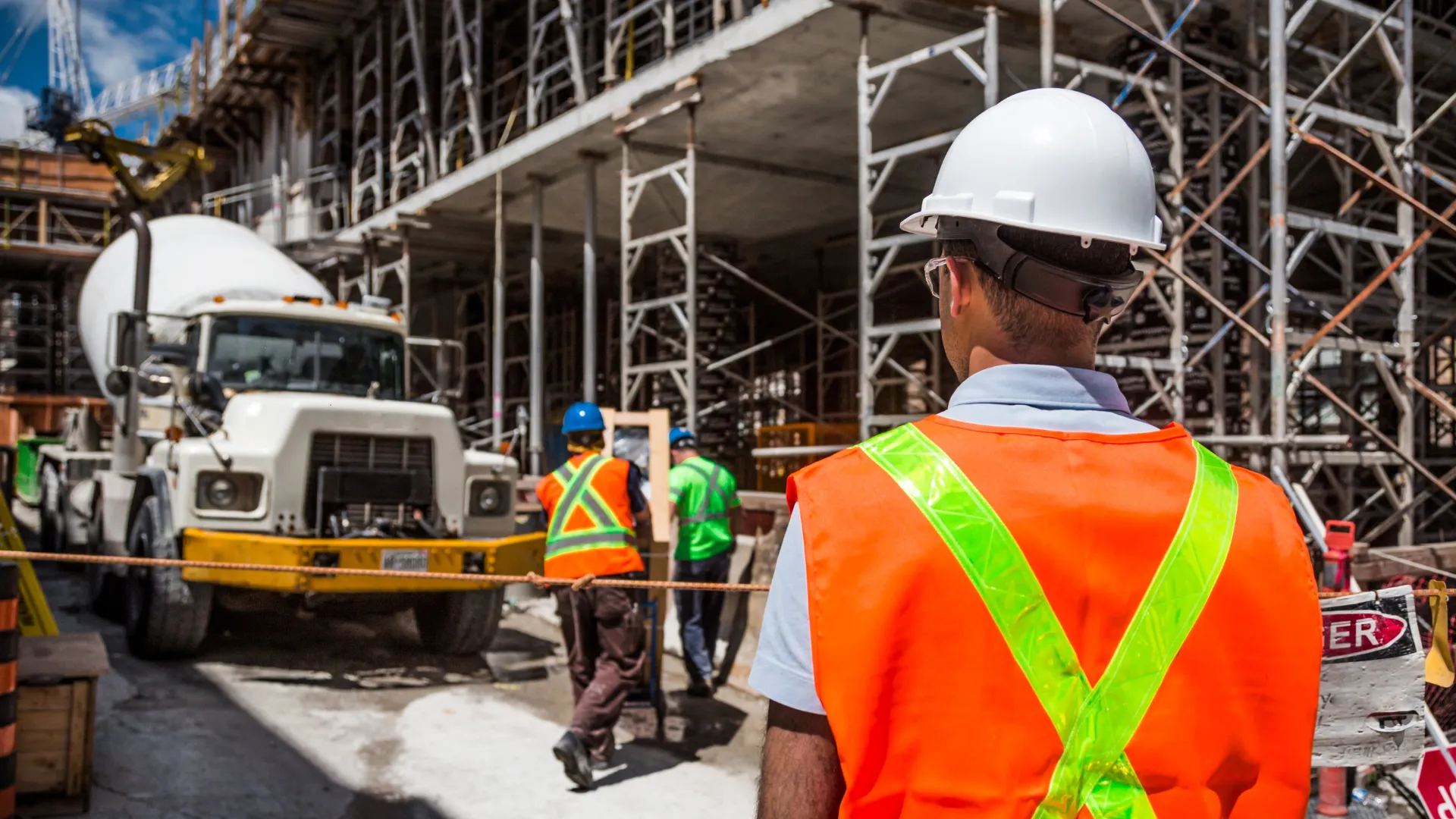 A site supervisor watches a concrete truck arrive at an active job site