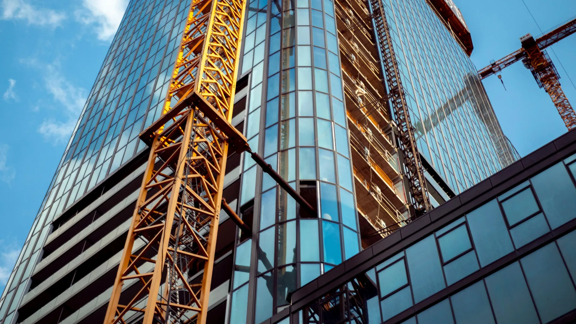 A tower crane rises beside a glass commercial building