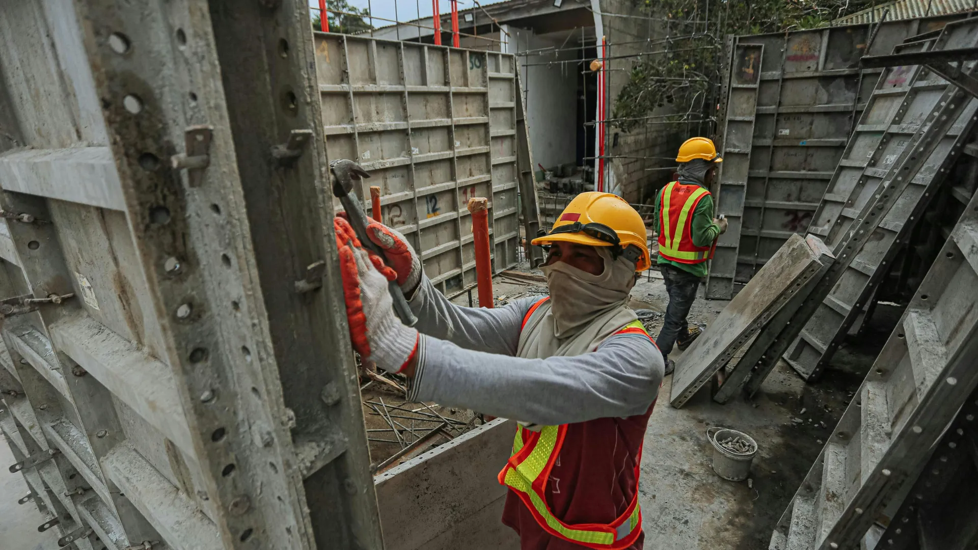 A worker fastens metal formwork on a concrete commercial site