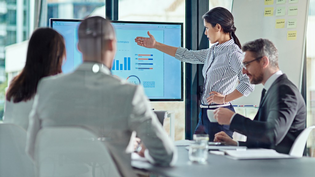 A woman presents campaign charts to colleagues in a meeting room