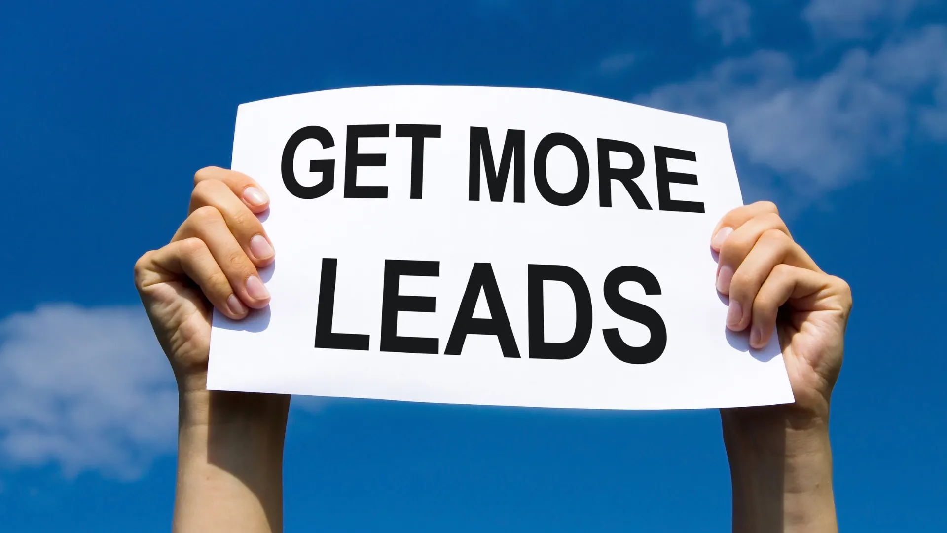 Hands hold a sign that reads Get More Leads