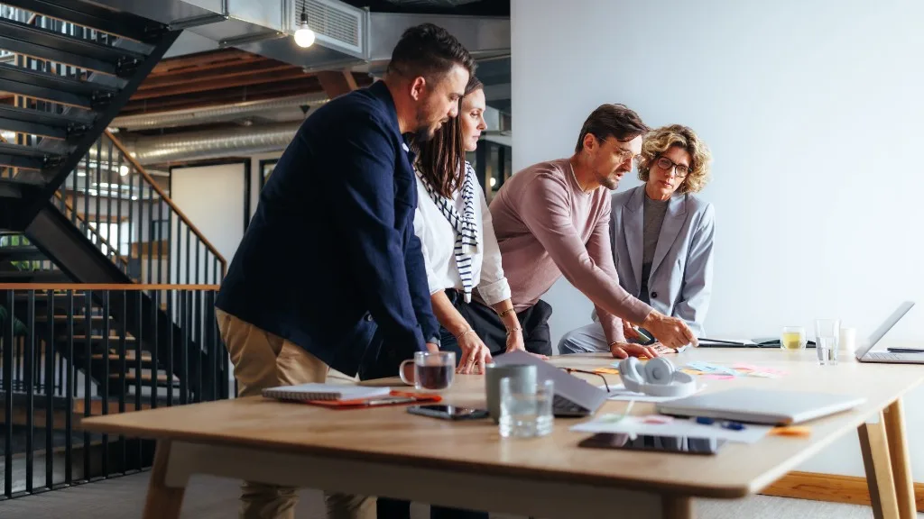 A team reviews notes and a laptop around a conference table