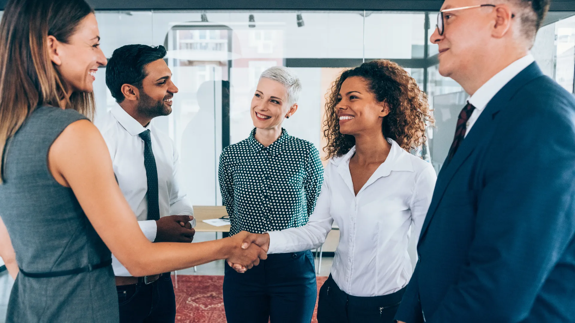 Colleagues shake hands during a meeting in a bright office