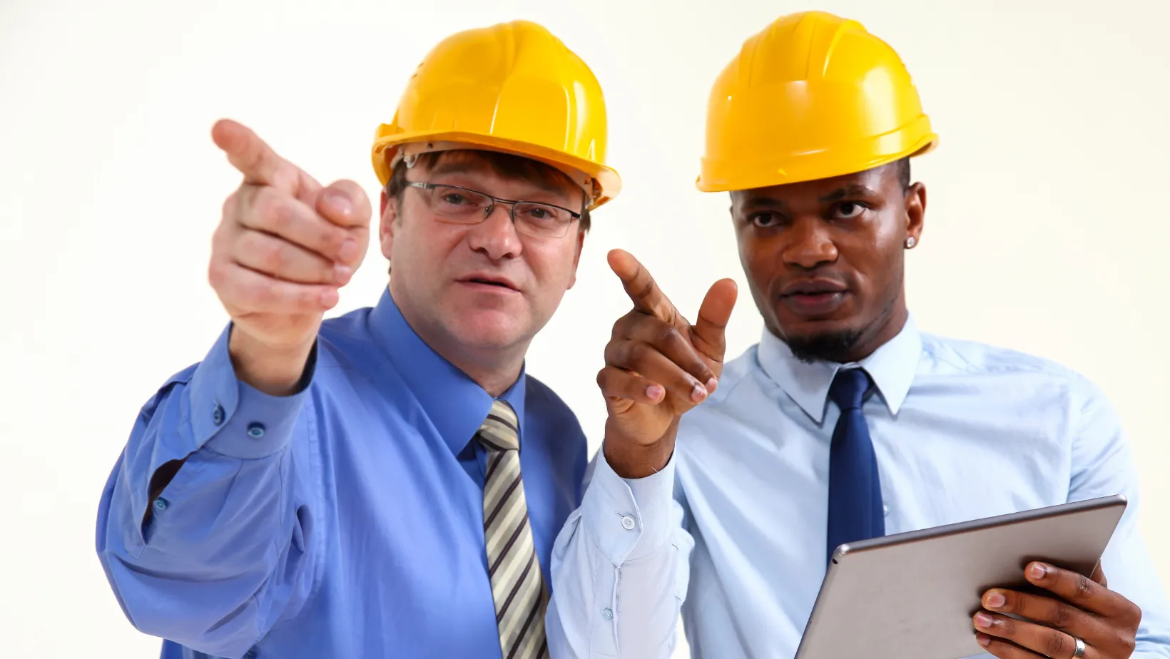 Two contractors in yellow hard hats pointing ahead, one holding a tablet