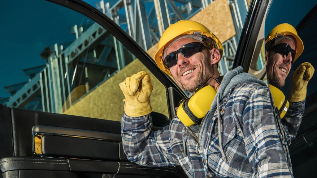 Contractor in a hard hat leaning from a truck at a building site