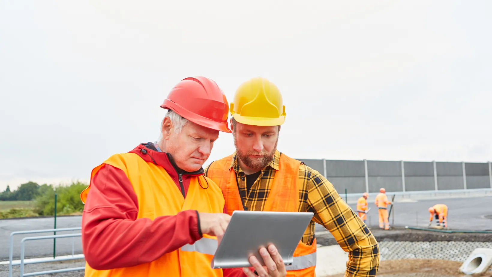 Two construction workers checking a tablet on a job site