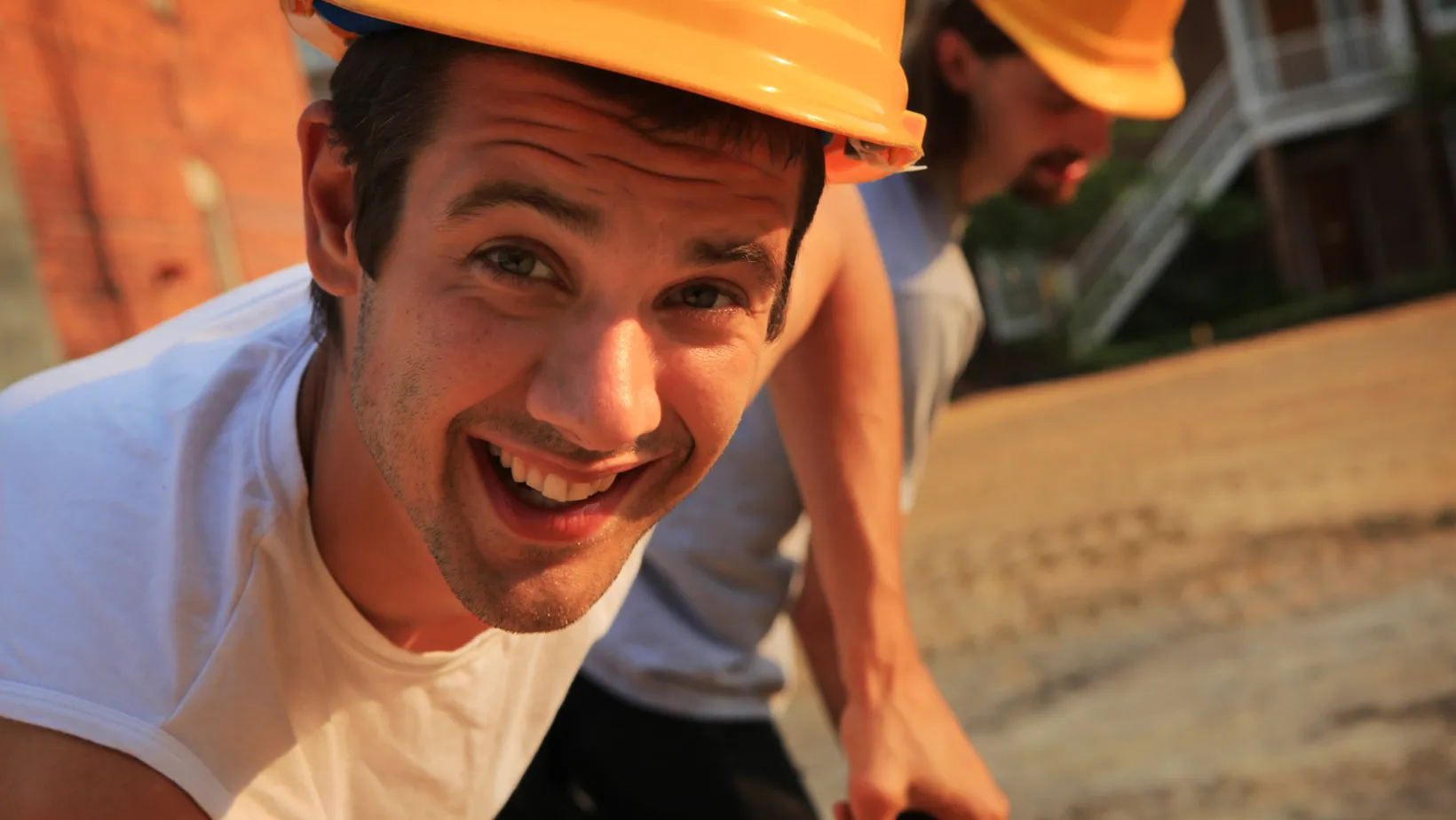 Two workers in yellow hard hats on a job site