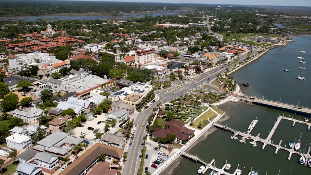 Aerial view of St. Augustine waterfront with historic red-tile roofs, marina docks, and the Bridge of Lions