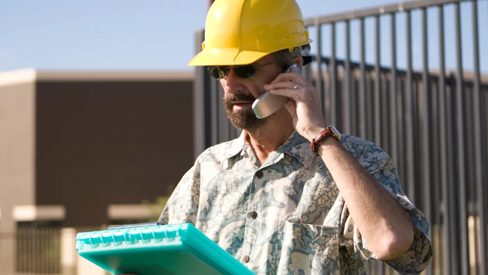 Roofer in a safety harness nailing asphalt shingles on a pitched roof