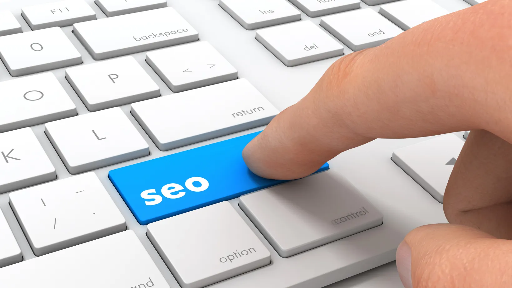 Finger pressing a blue SEO key on a white keyboard