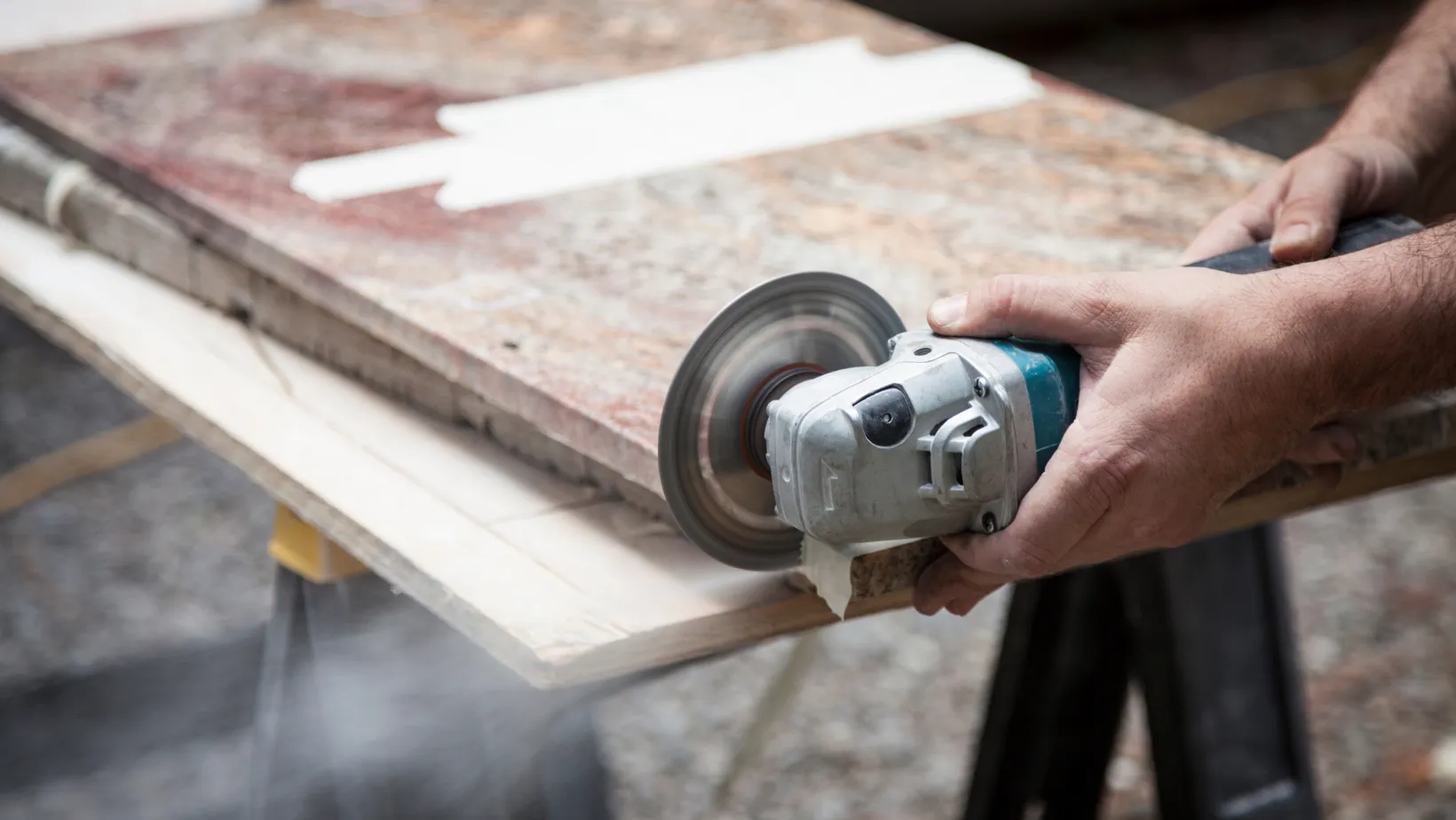 A fabricator cutting a stone slab with an angle grinder.