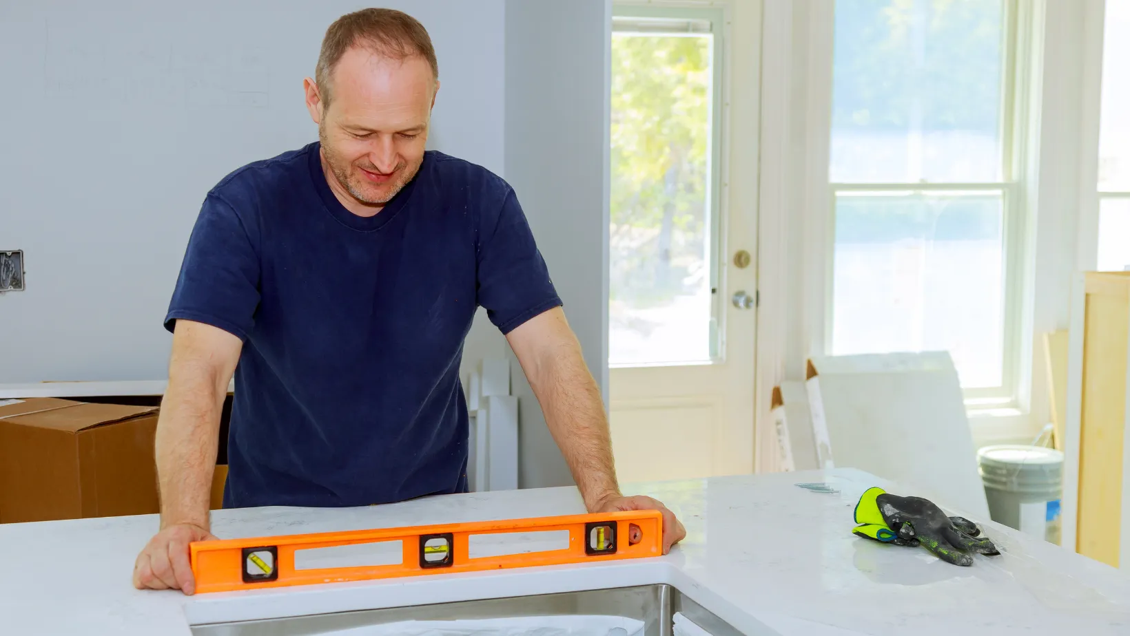 An installer checking a white countertop with an orange level.