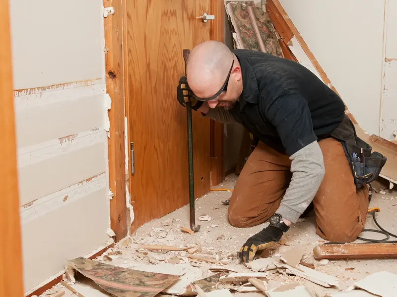 A full house remodeling contractor removes the old door frame of a house.