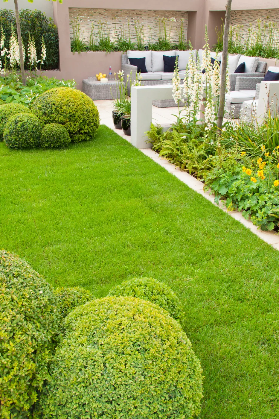 Homeowner reviewing a landscaped backyard design on a tablet, illustrating seasonal landscaping search behavior and purchase intent.