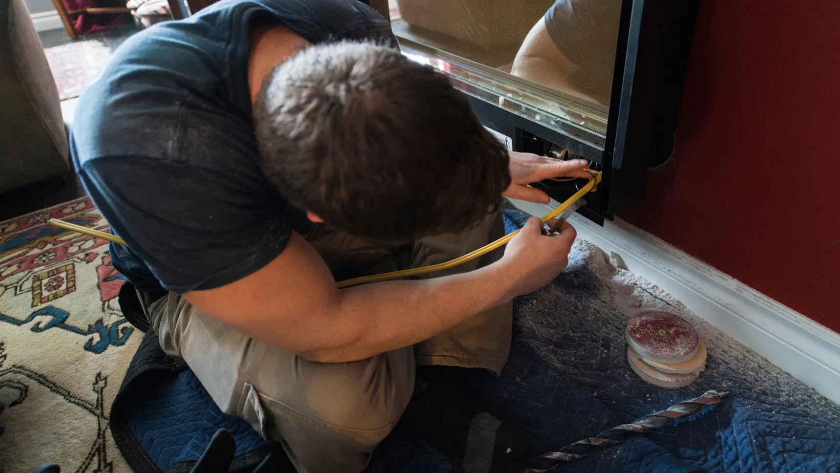 A technician connecting a gas line behind a fireplace