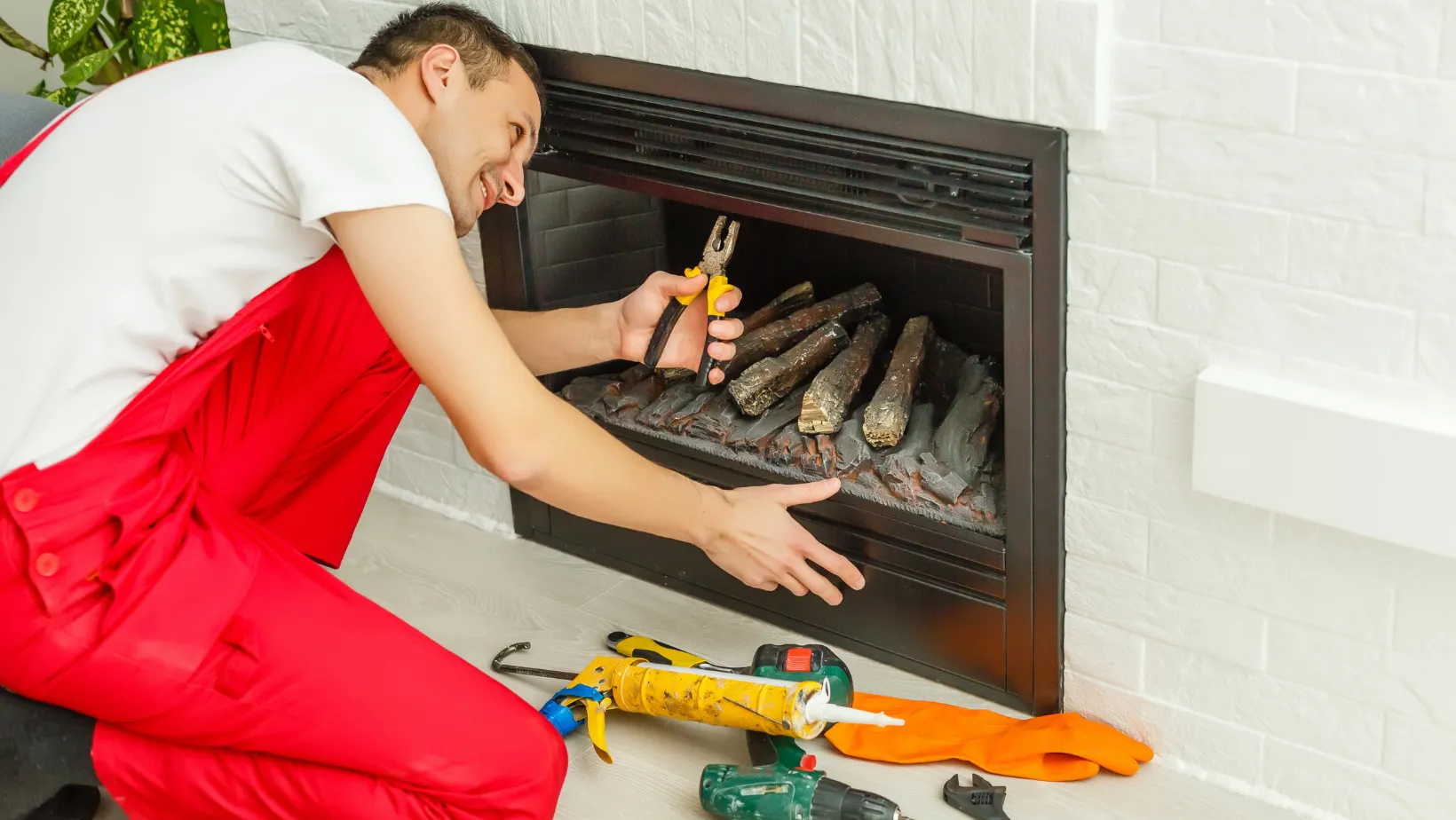 A technician using pliers on a fireplace log set