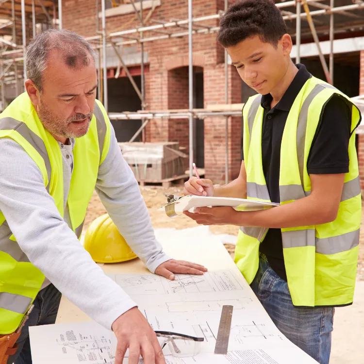 Construction professionals reviewing blueprints and notes at a building site