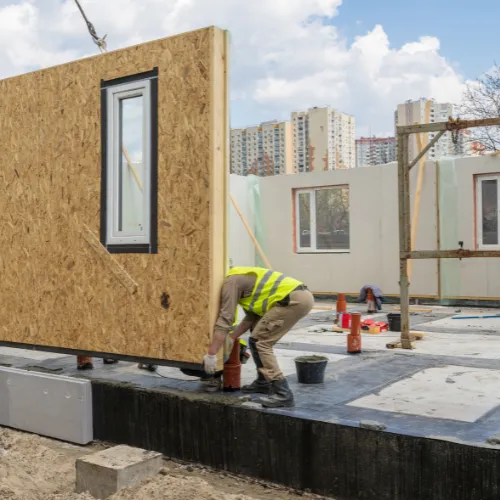 Workers installing a modular building panel on a construction site