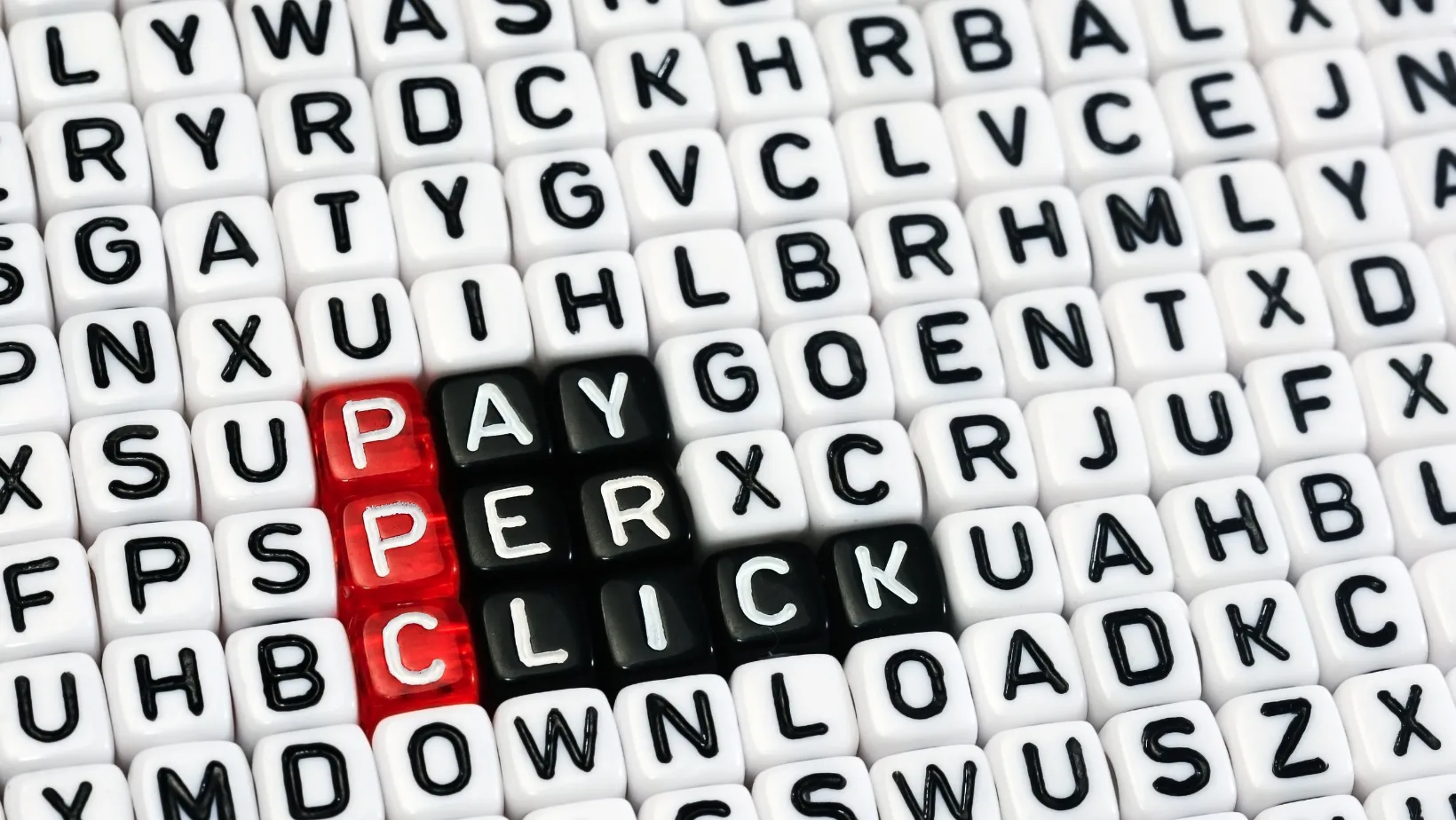 Red PPC letter beads beside black Pay Per Click beads among white letter blocks