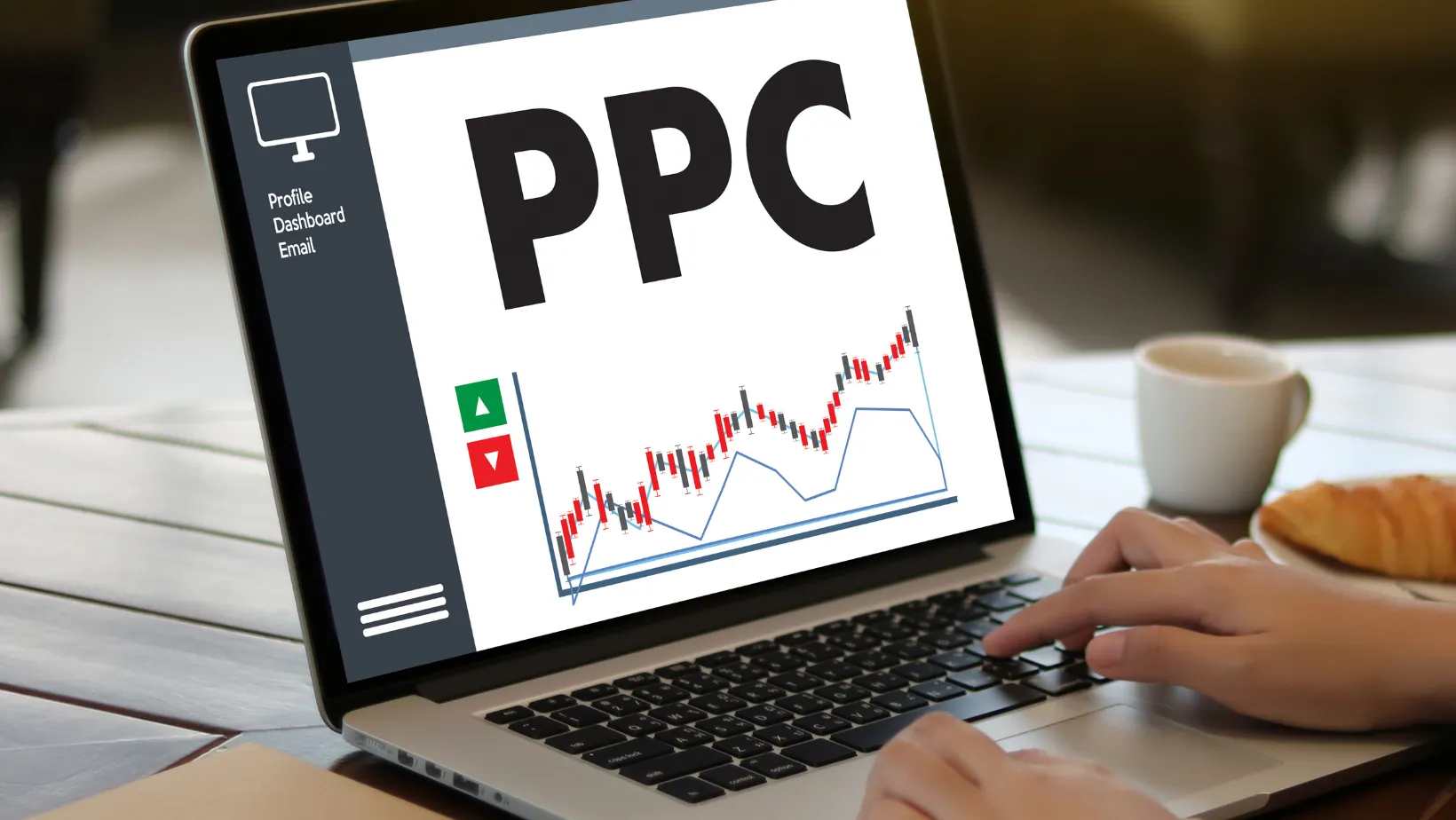 Hand typing on a laptop showing a PPC dashboard with a rising performance chart