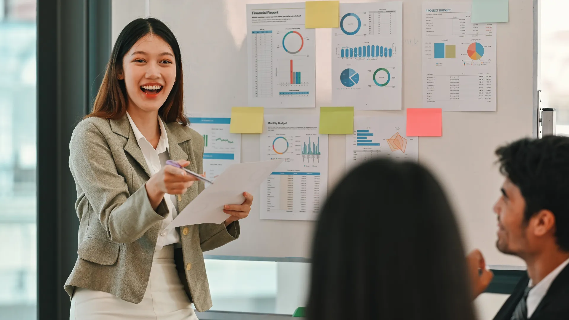 A presenter smiles while reviewing financial charts with a team
