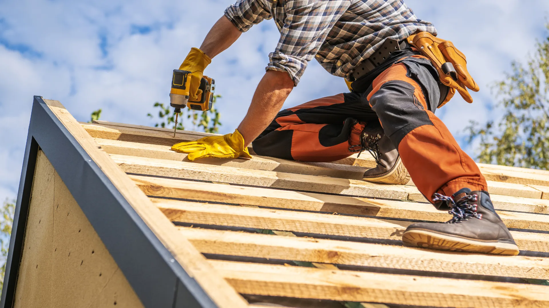 A roofer fastening boards on a new roof deck