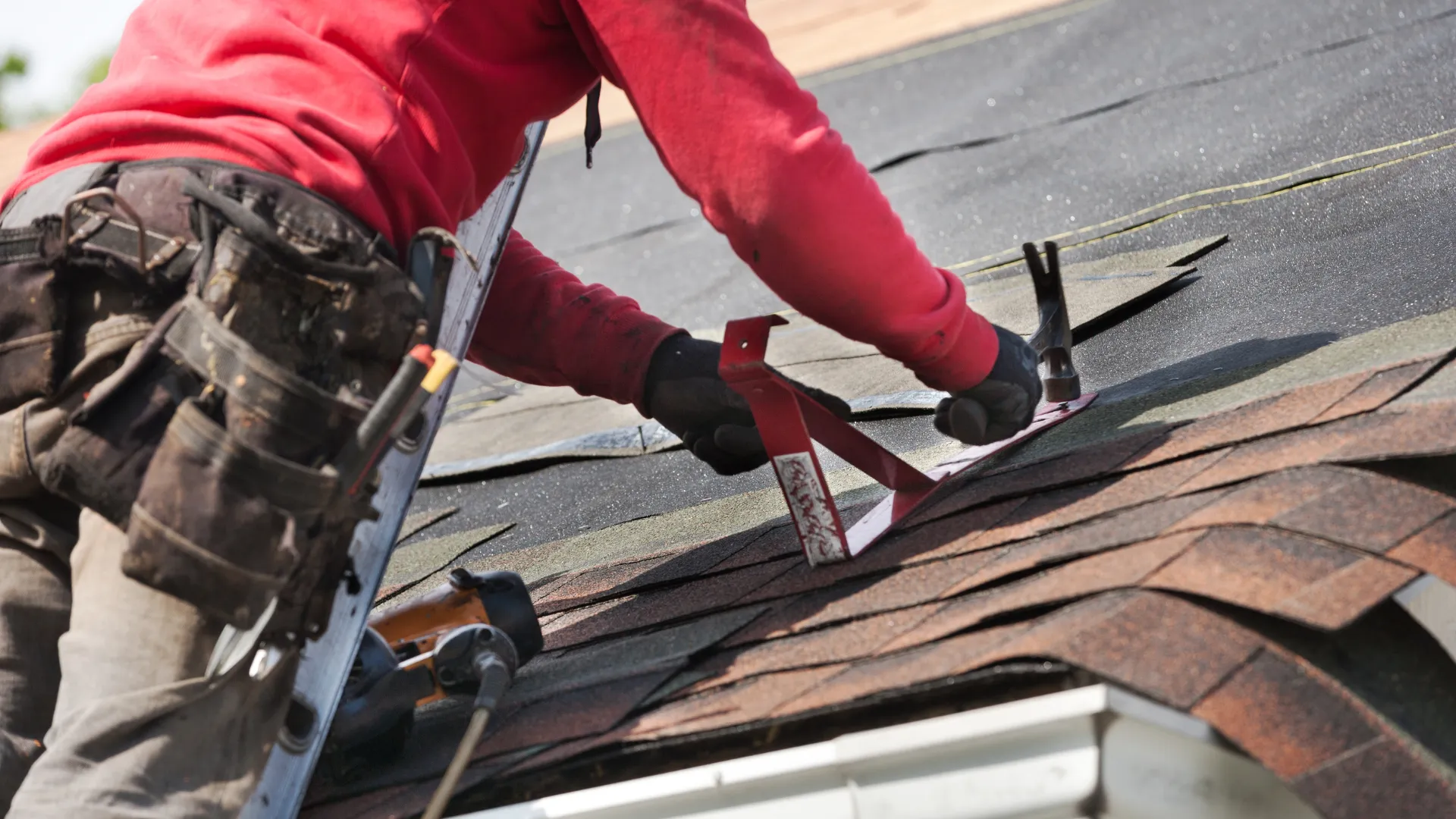 A roofer installing shingles on a residential roof