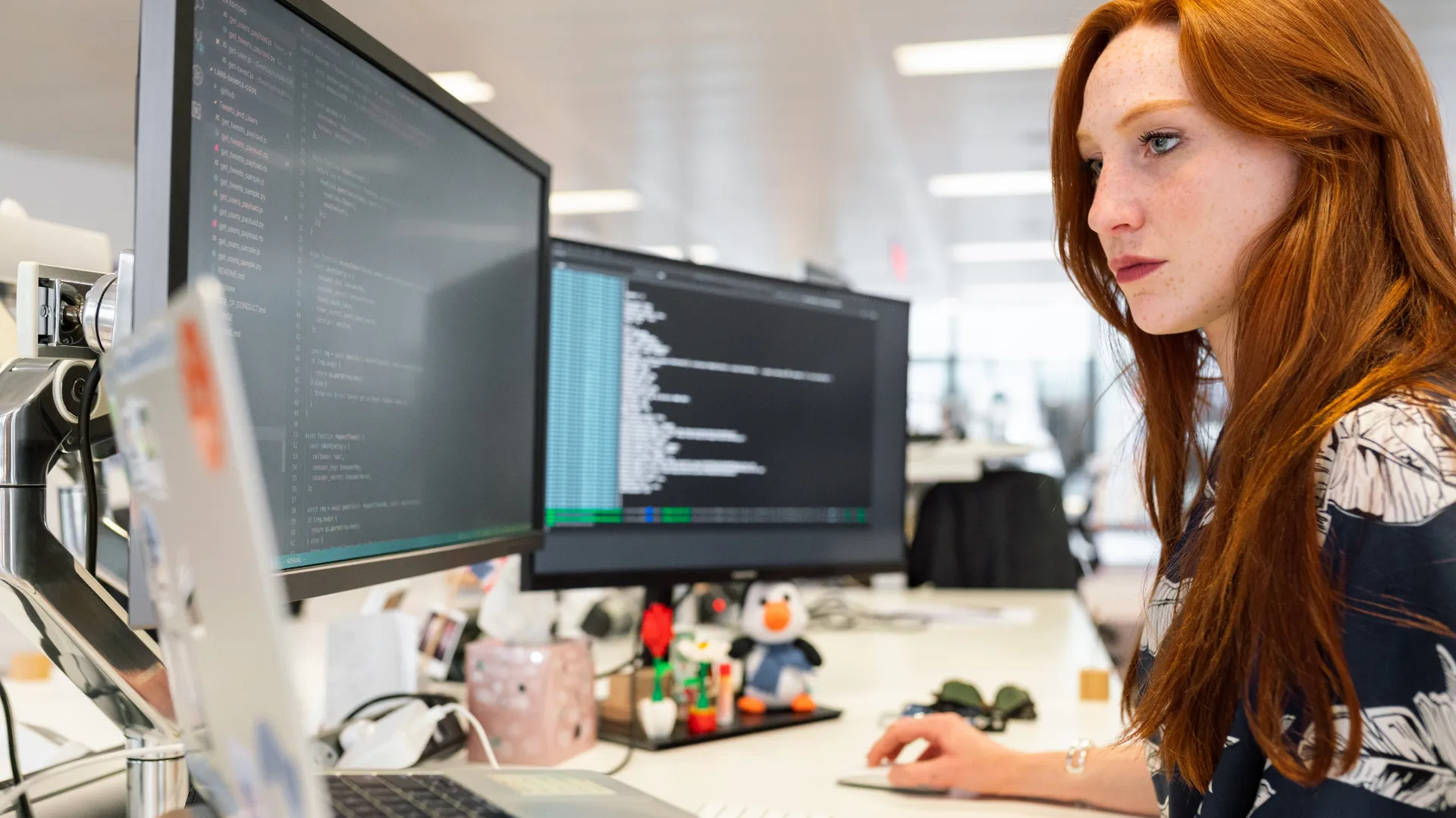 A specialist reviewing code and data on two monitors