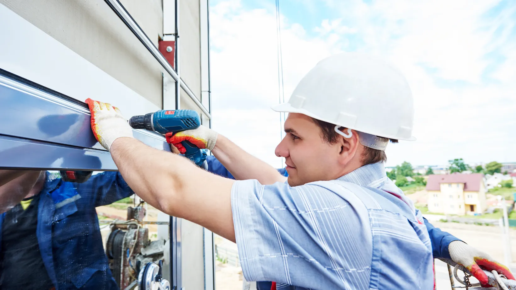 A contractor drilling siding in place beside a window